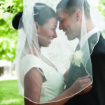 Bride and groom hugging under veil